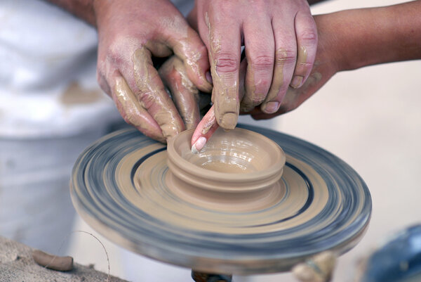 Hands working on pottery wheel