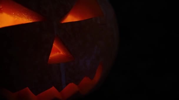 La calabaza de Halloween arde, brilla y brilla desde el interior sobre un fondo negro — Vídeo de stock