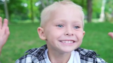 Kafkas sarışının portresi çimlerin üzerinde zıplayan ve parkta surat yapan küçük çocuk. Mutlu çocukluk kavramı. 4K ağır çekim.