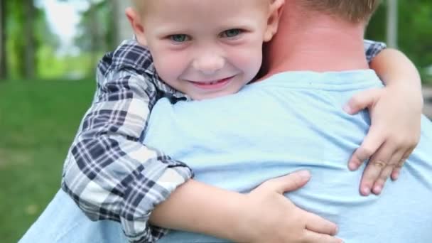 Szczęśliwy biały blondyn obejmuje swojego ojca. Portret szczęśliwego dziecka. Rodzina w parku. Edukacja, troska. przytulając tatę. ojcostwo i koncepcja miłości — Wideo stockowe