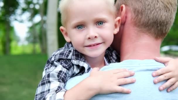 Caring happy young adult dad embracing small adorable preschool child son having trust conversation cuddling outdoor in park, loving father enjoy with little kid boy – Stock-video
