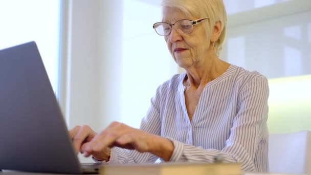 Senior mulher idosa madura trabalhando no laptop em casa de cozinha no escritório. senhora assistindo treinamento de negócios, webinar on-line no computador. trabalho remoto ensino à distância social a partir de casa. Mulher dos anos 60 — Vídeo de Stock