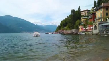 Lombardy, İtalya 'da Como Gölü' nde küçük dalgalarda sallanan demirli tekne ve botların kısa bir klibi. Birkaç mavi gökyüzü lekesi olan bulutlu bir yaz günü. 4K