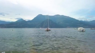 Lombardy, İtalya 'da Como Gölü' nde küçük dalgalarda sallanan demirli tekne ve botların kısa bir klibi. Birkaç mavi gökyüzü lekesi olan bulutlu bir yaz günü. 4K