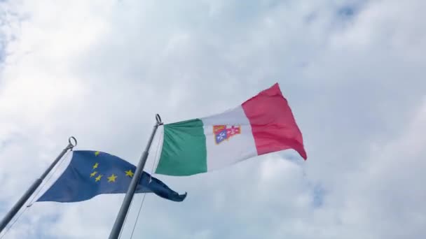 ヨーロッパ連合の旗とイタリアの旗を持つ短いクリップは イタリアのロンバルディア州のコモで 互いに隣に 風に手を振っています 曇り空の夏の日です 4Kクリップ — ストック動画