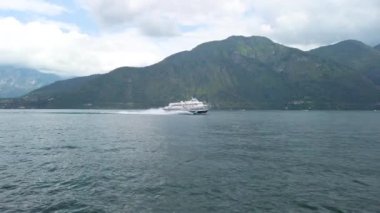 Como Gölü 'nde yelken açarken, diğer yönden gelen hızlı bir turist feribotundan kısa bir atış. Hava bulutlu, bulutlu bir yaz günü. 4K ağır çekim