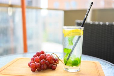 Limonlu ve nane şekerli içecek. Terasta, olgun kırmızı üzümlerle birlikte servis edildi. Sıcak, güzel bir yaz günü..