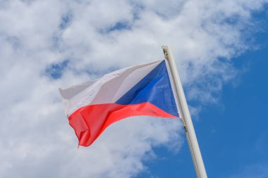 Czech Republic flag waving in the wind. It is a beautiful sunny summer day, with blue sky and white clouds in the background.