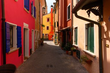 Various streets, Caorle, Veneto, Italy. July 27 2022. Editorial stock picture of the streets, alleys and very colorful small houses in the town on Caorle, Italy. Caorle is a tourist town, known for these multi colored houses. It is a beautiful sunny 