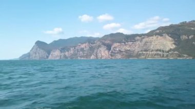 Garda gölü kıyısındaki Malcesine şehrine doğru yol alıyoruz. Turist feribotundan gölün etrafındaki dağlara doğru çekilmiş. Güneşli güzel bir yaz günü. 4K stok video