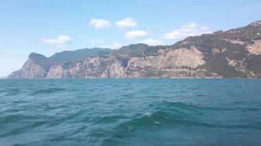 Garda gölü kıyısındaki Malcesine şehrine doğru yol alıyoruz. Turist feribotundan gölün etrafındaki dağlara doğru çekilmiş. Güneşli güzel bir yaz günü. 4K stok video