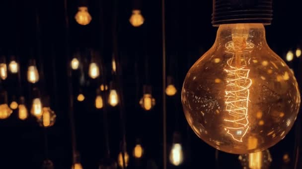 Flickering moda antiga tungstênio Edison lâmpada lâmpada sobre fundo preto. câmera lenta tiro 4K. — Vídeo de Stock