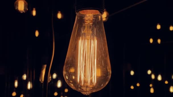 黒の背景に古いファッションタングステンエジソン電球ランプをフリッカー。スローモーションショット｜4K. — ストック動画
