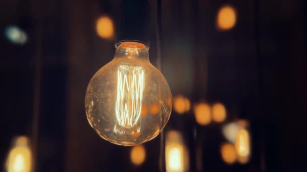 Parpadeante lámpara de bombilla de tungsteno Edison de la vieja moda sobre fondo negro. Disparo en cámara lenta 4K. — Vídeo de stock