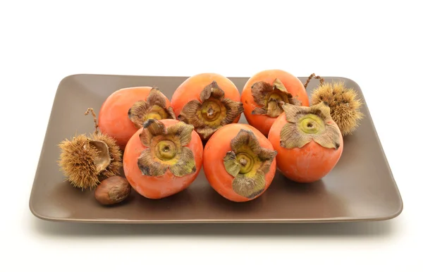 Persimmons in brown plate — Stock Photo, Image