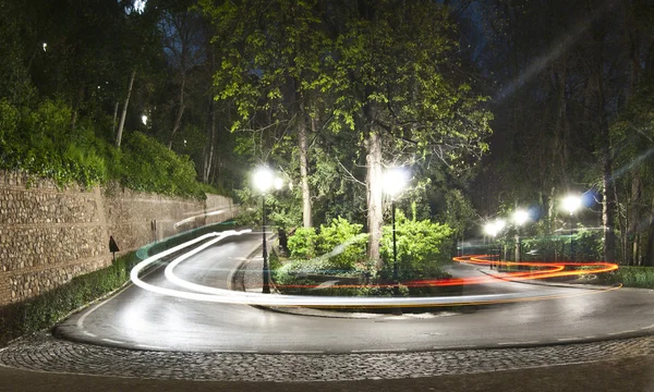 Route courbe la nuit dans la forêt de l'Alhambra avec feux arrière taxi — Photo