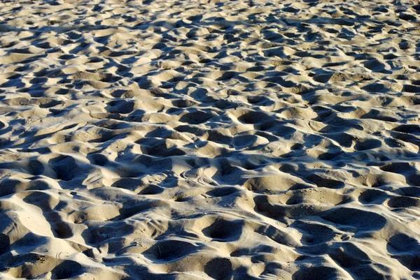Praia de areia com luzes de pôr do sol e sombras, como fundo — Fotografia de Stock