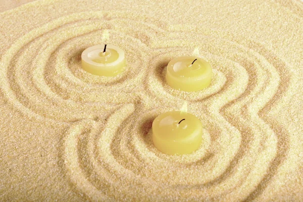 三个点燃的黄色蜡烛插在沙滩上 — 图库照片