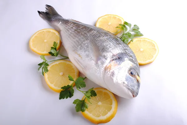 Raw sea fish with lemon slices and parsley — Stock Photo, Image