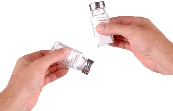 Due mani tengono uno shaker di sale, isolato su bianco — Foto Stock