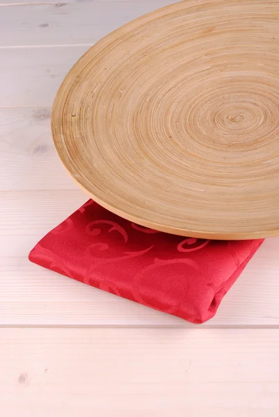 Wooden round dish over a red napkin — Stock Photo, Image