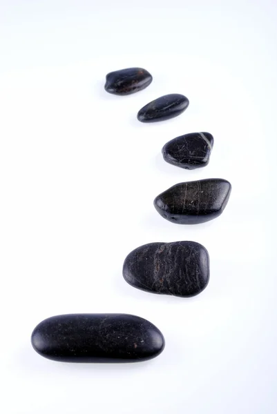 Schwarze Zen-Steine auf weißem Hintergrund, weiche Schatten Stockbild