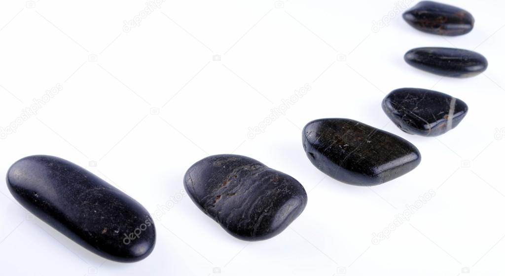 Black zen stones on white background, soft shadows