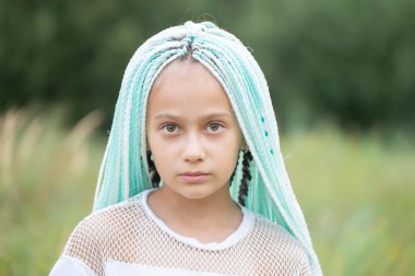 Çok renkli Afrika örgüleri olan şık küçük bir kız kameraya bakar..