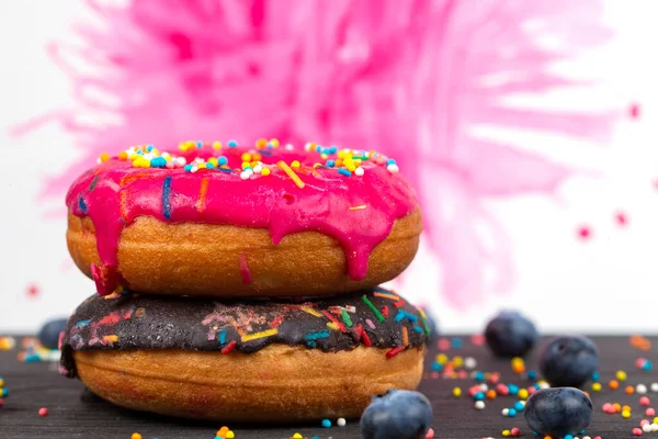 Creative sweet food. Bright donuts with multi-colored sprinkles on a colorful background.