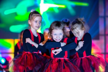 Küçük kızlar dans gösterisi yapıyor. Kırmızı elbiseli Helovinna için dans et. Kız dansı. Bir çocuk dans grubunun duygusal performansı.