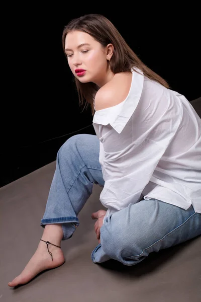 Beautiful Girl White Shirt Jeans Sits Gray Background — Stock Photo, Image
