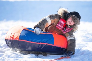 Kar kaydırağında kayan mutlu küçük çocuk. Kışın çocuk.