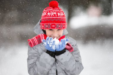 Elinde kar tutan mutlu çocuk. Çocuk kışın ve ilk karın keyfini çıkarır..