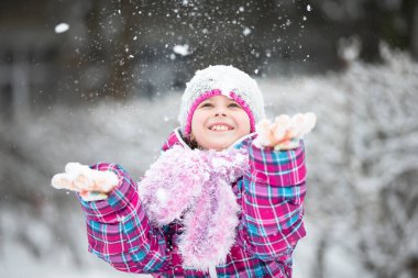 Mutlu kız kar atıyor. Çocuk kışın ve ilk karın keyfini çıkarır..