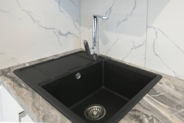 Mutfakta siyah mermer lavabo ve musluk var..