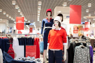 Beyaz örgü şapkalı ve kırmızı kazaklı mankenler. Kadın kıyafetleri satışı.