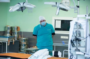 A doctor in a surgical suit stands in the operating room among the equipment.Portrait of surgeon in the operating room