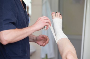 Doktor hastanın bacağını bandajlar. Ameliyattan sonra cerrah ve hasta..