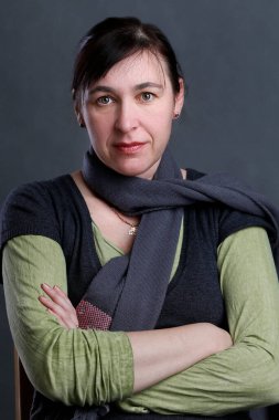 Portrait of a middle-aged woman on a gray background. Woman forty years looking at the camera.