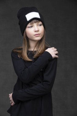 Beautiful little girl in a knitted hat on a dark background.