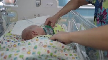 A newborn in the hospital breathes into an oxygen mask.