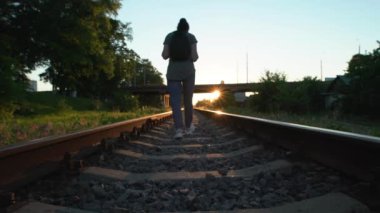 Rayların üzerindeki krasovki 'de kadın bacaklarına yakın çekim. Güzel, yaşlı bir kadın demiryolu boyunca yürüyor ve rayların üzerinde denge kuruyor..