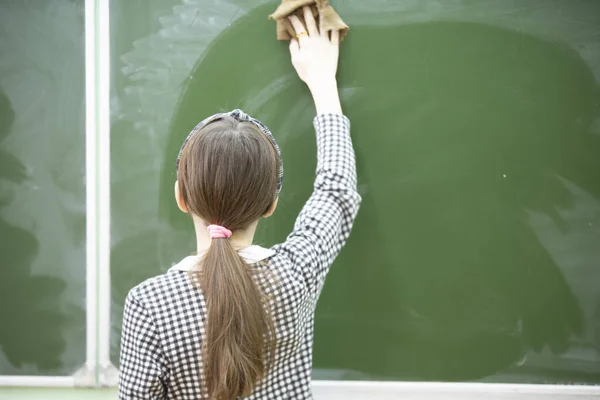 A middle school or junior high school student wipes the blackboard.