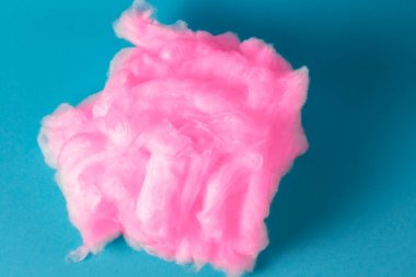 Mavi arka planda pembe pamuk. Yumuşak bir iplik yığını. Mavi üzerinde izole edilmiş pamuk parçası.
