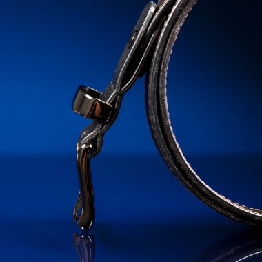 Black leather belt on a dark blue background.