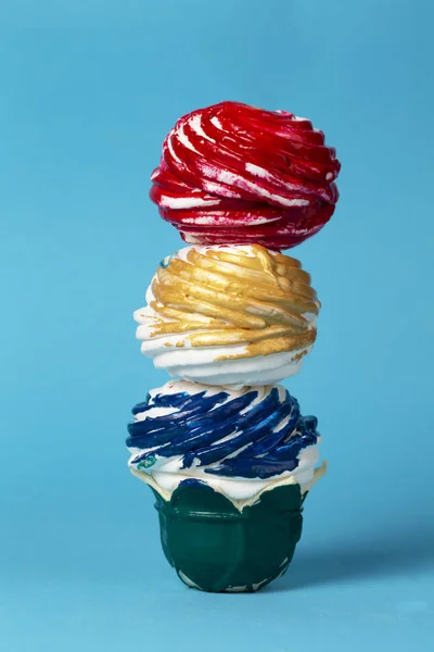 Colorful cake made of multi-colored glaze on a blue background. Creative sweet food. Beautiful unusual dessert.