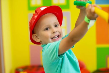 A little boy in a protective helmet plays a builder.