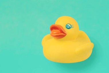 Yellow rubber vintage duck for swimming on an emerald background.