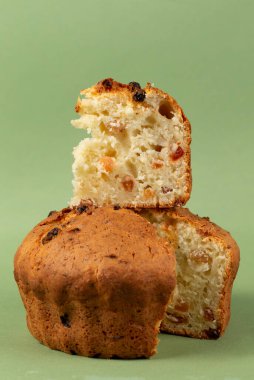 Classic cottage cheese pie with raisins.Cupcake with a cut piece on a green background.