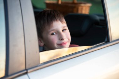 Arabada bir çocuk var. Küçük bir çocuk arabanın camından dışarı bakıyor..